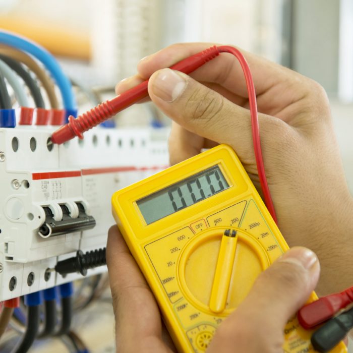 A person is holding a multimeter in their hand.