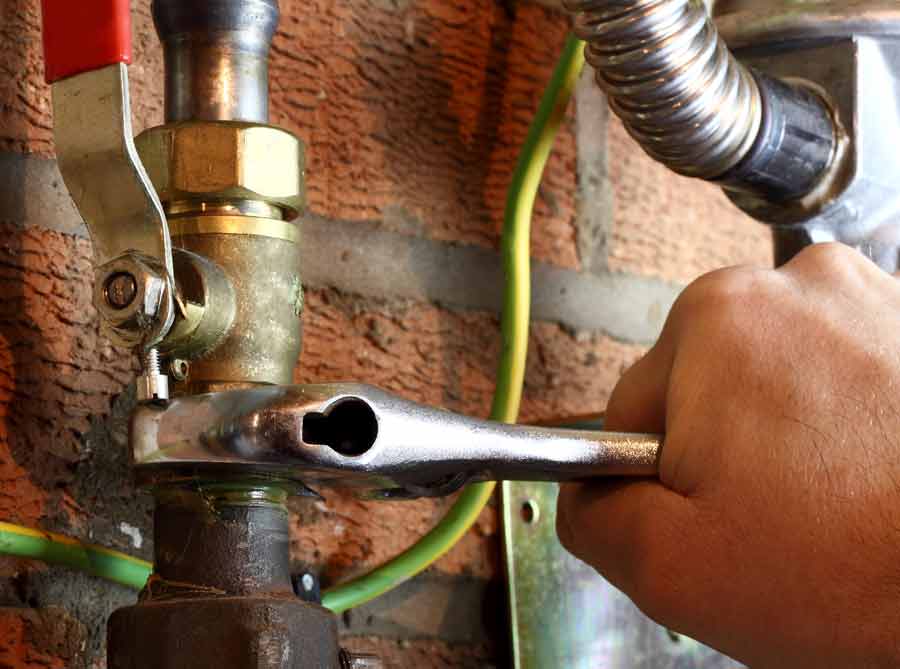 A person is working on the pipes of an industrial type water heater.